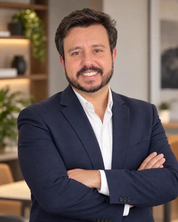 Bruno Marinho de braços cruzados, sorrindo, no escritório