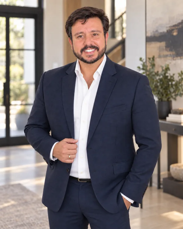 Bruno Marinho em pé em ambiente interno, de terno azul e camisa branca